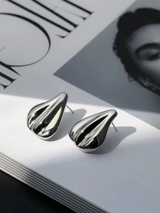 Detailed view of silver teardrop stud earrings on a fashion magazine with high polish