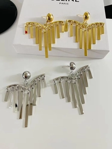 Detail of layered gold and silver tassel earrings with geometric pine needle fringe drops