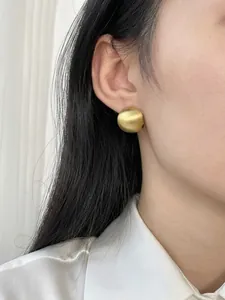 Detail of matte gold brushed semi-sphere earrings on model with elegant minimalist style