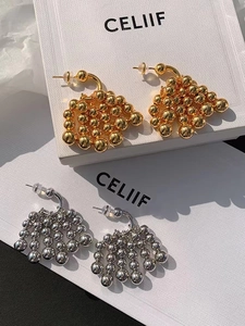 Macro view of gold and silver grape bunch tassel earrings with polished metallic spheres