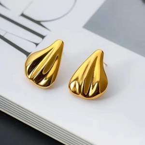 Minimalist gold textured teardrop earrings with elegant radial stripes on white background