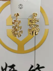 Detailed view of golden ginkgo leaf dangle earrings with a textured hammered finish