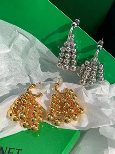 Detail of gold and silver grape cluster earrings on signature green gift packaging