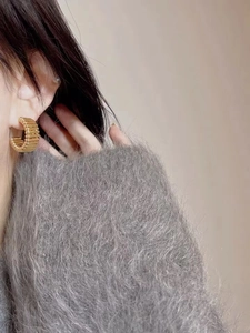 Gros plan de boucles d'oreilles dorées en forme de C avec texture rainurée sur mannequin