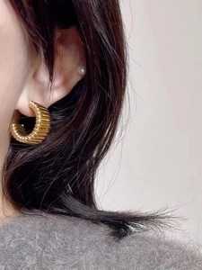 Détail de boucles d'oreilles dorées en forme de C avec finition métal vintage