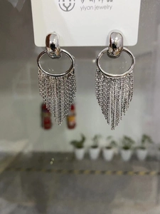 Macro shot of silver tassel earrings with multiple fine metal chains on a display card