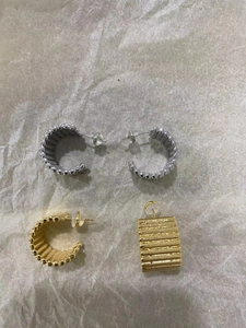 Détail des boucles d'oreilles en forme de C en métal doré et argenté avec texture