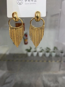 Close-up of gold tassel drop earrings with crescent design and long chain fringes