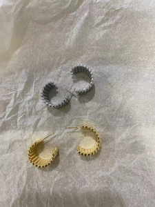 Détail de boucles d'oreilles perlées en forme de C en or et argent au fini poli