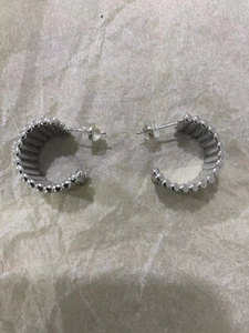 Détail de boucles d'oreilles en C argentées avec texture perlée et fermoirs silicone