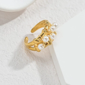 Détail macro d'une bague ouverte dorée style bambou avec cinq perles blanches