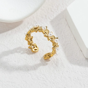 Gros plan d'une bague étoile dorée avec de petites perles blanches sur fond marbre