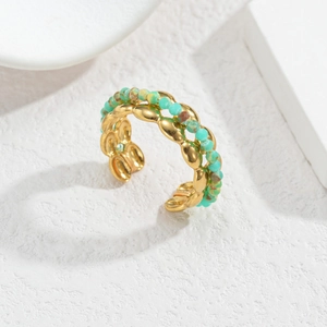 Détail de la bague ouverte dorée avec des perles turquoise et une texture de métal ondulé