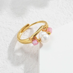 Detail of adjustable gold ring featuring a large white pearl and pink square beads