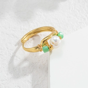 Macro detail of a baroque pearl ring with emerald green beads and gold plated wire wrap