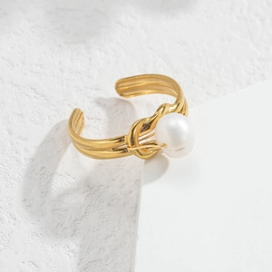 Detailed close-up of a gold pearl ring with a twisted rope band design on stone texture