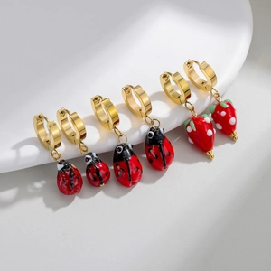 Three pairs of gold-plated hoop earrings with red strawberry and ladybug enamel charms