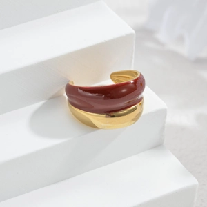 Nahaufnahme eines breiten goldenen Rings mit satter weinroter Emaille-Beschichtung oben