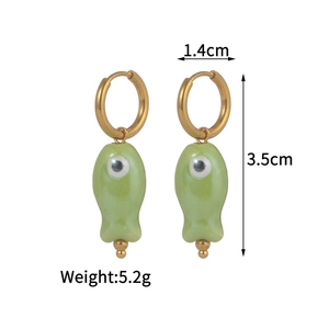 Detail view of gold hoop earrings with light green ceramic fish pendants measuring 1.4x3.5cm