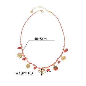 Detail view of woven cord necklace with gold charms including sun and clover symbols