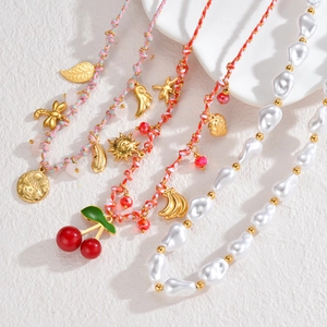 Colorful woven necklaces with cherry pendants and baroque pearl beads on white background