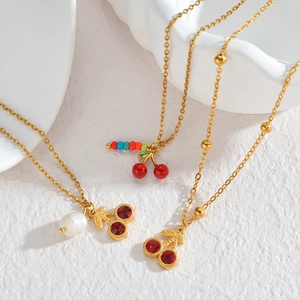 Trois colliers cerise en acier inoxydable plaqué or 18K avec strass rouges et perles