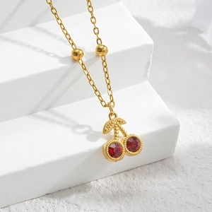 Collier élégant en chaîne dorée avec pendentif cerise rouge sur fond blanc