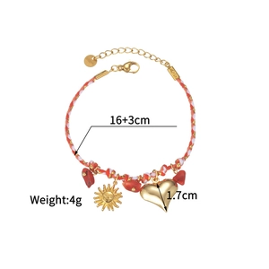 Detail of woven rope bracelet with gold sun charms and red stones measuring 16+3cm