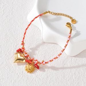 Colorful woven cord bracelet with gold pendants and red stones on a white background