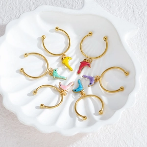 Set of 7 gold ocean dolphin charms hoop earrings displayed in a white shell tray