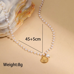 Détail du collier de perles baroques avec pendentif feston doré posé sur un grand coquillage