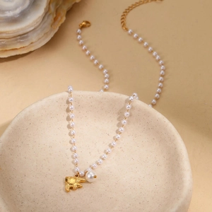 Collier de perles baroques avec pendentif poisson doré sur un bol en céramique