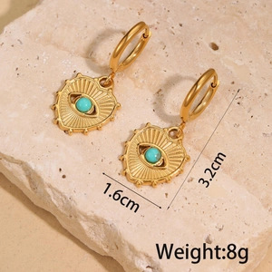 Detail of gold heart earrings with turquoise evil eye on a natural stone base