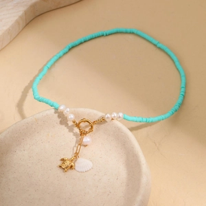 Detail of vintage beaded necklace with golden sea turtle and white scallop pendants
