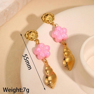 Detail view of 55mm shell tassel earrings with flower studs on beige display tray