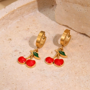 Fruit themed cherry drop earrings with gold hoops on a textured stone background