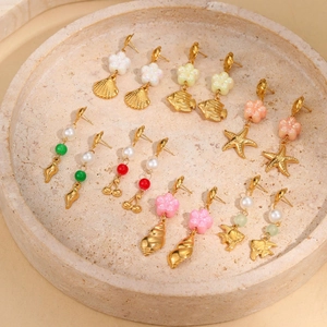 Detailed view of gold ocean-themed earrings featuring shells, starfish and floral designs