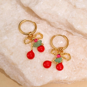 Detail showing cherry pendant earrings with gold bows on natural stone background