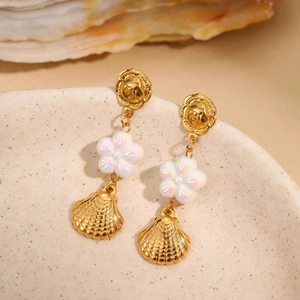 Golden sea-themed drop earrings with white flower and scallop shell charms on ceramic