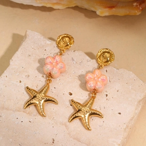 Detailed close-up of long gold earrings with pink resin petals and starfish pendants