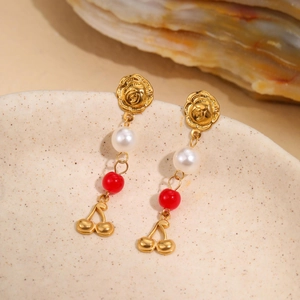 Detail of gold rose stud earrings with pearl, red bead, and cherry pendants