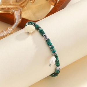Dettaglio del bracciale con perline verdi, ciondolo a conchiglia e perla barocca naturale