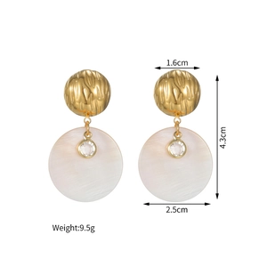 Détail de boucles d'oreilles boules dorées 18k avec disque nacre et pierre zircon