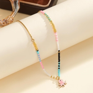 Detail of beaded necklace featuring golden chain and pink enamel octopus pendant