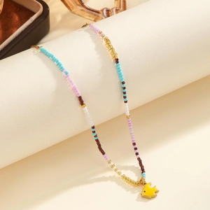 Detail of bohemian beaded necklace featuring a vibrant yellow fish enamel pendant