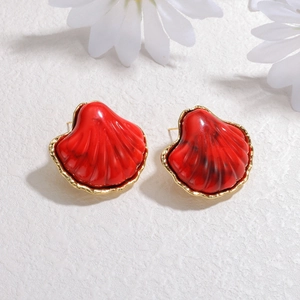 Elegant red shell stud earrings with gold plating on a textured white background