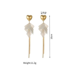 Détail des boucles d'oreilles cœur dorées à pompons avec pétales de nacre et dimensions