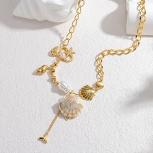 Collana marina dorata con pendenti a conchiglia e perle su base bianca testurizzata
