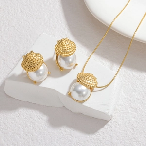 18k gold plated shell pearl jewelry set featuring necklace and earrings on white stone