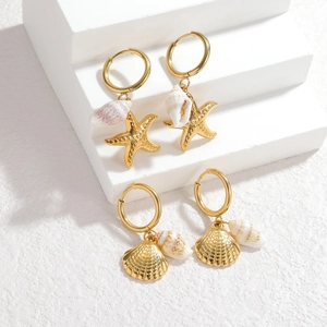 18k gold ocean starfish and shell drop earrings on a minimalist white display